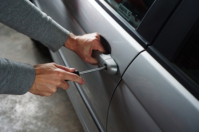 Les mains d'un homme tiennent un tournevis pour forcer la serrure d'une voiture