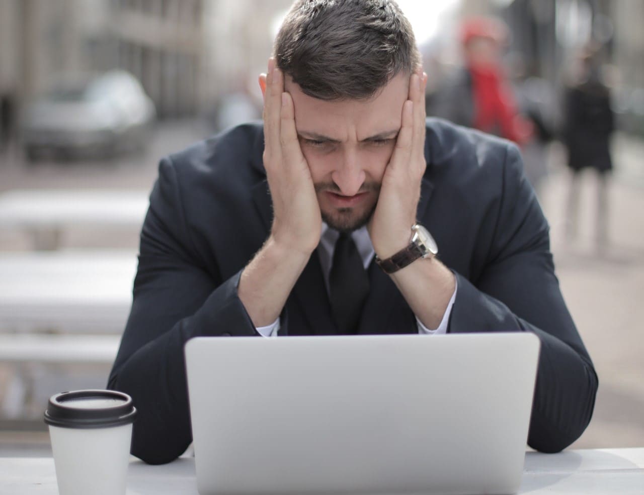 Homme qui regarde son ordinateur d'un air choqué. Il se tient la tête