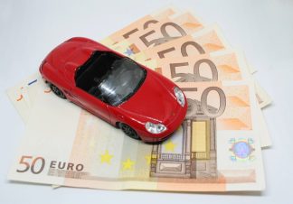 petite voiture rouge placé sur des billets de banque pour symboliser la fiscalité des voitures de fonction