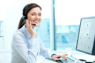 Une femme, gestionnaire de flotte devant son ordinateur et répondant via son casque à un appel téléphonique.
