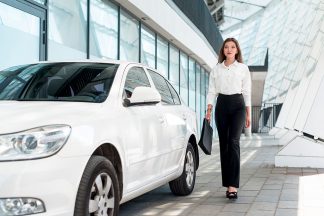 une femme marchant dans la rue à coté d'une voiture